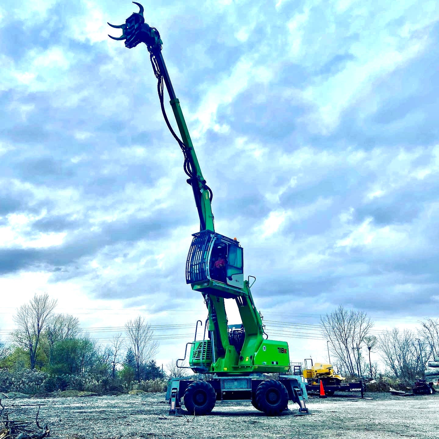 Green Sennebogen Tree Handler with Extended Crane in Action