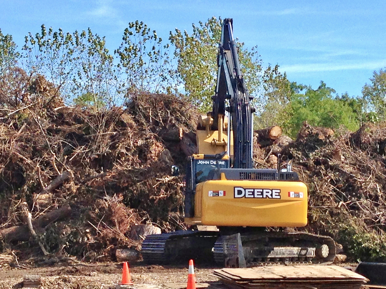 Yellow John Deere Tractor Piling Tree Debris into Massive Heap