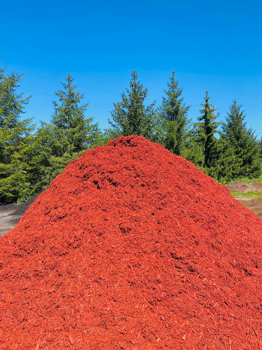 Premium dyed red mulch in a large pile at Raney Tree Care facility in Moline, IL